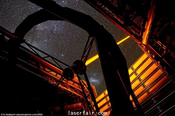 智利歐洲南方天文臺帕拉納爾天文臺操作的這個新PARLA激光器。從圖上可以看到，7瓦特激光器發(fā)出的橙黃色光束從甚大望遠(yuǎn)鏡的望遠(yuǎn)鏡4的穹隆結(jié)構(gòu)射向高空。在背景圖上還能看到大麥哲倫云