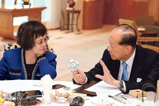 李嘉誠（右）在接受媒體訪問時指出，長實集團以香港為基地，常常積極在港尋找投資機會，但是政府很多政策，需時消化。圖為他向財新傳媒總編輯胡舒立介紹他本周的“最愛”納米LED燈泡。圖片來源：香港明報
